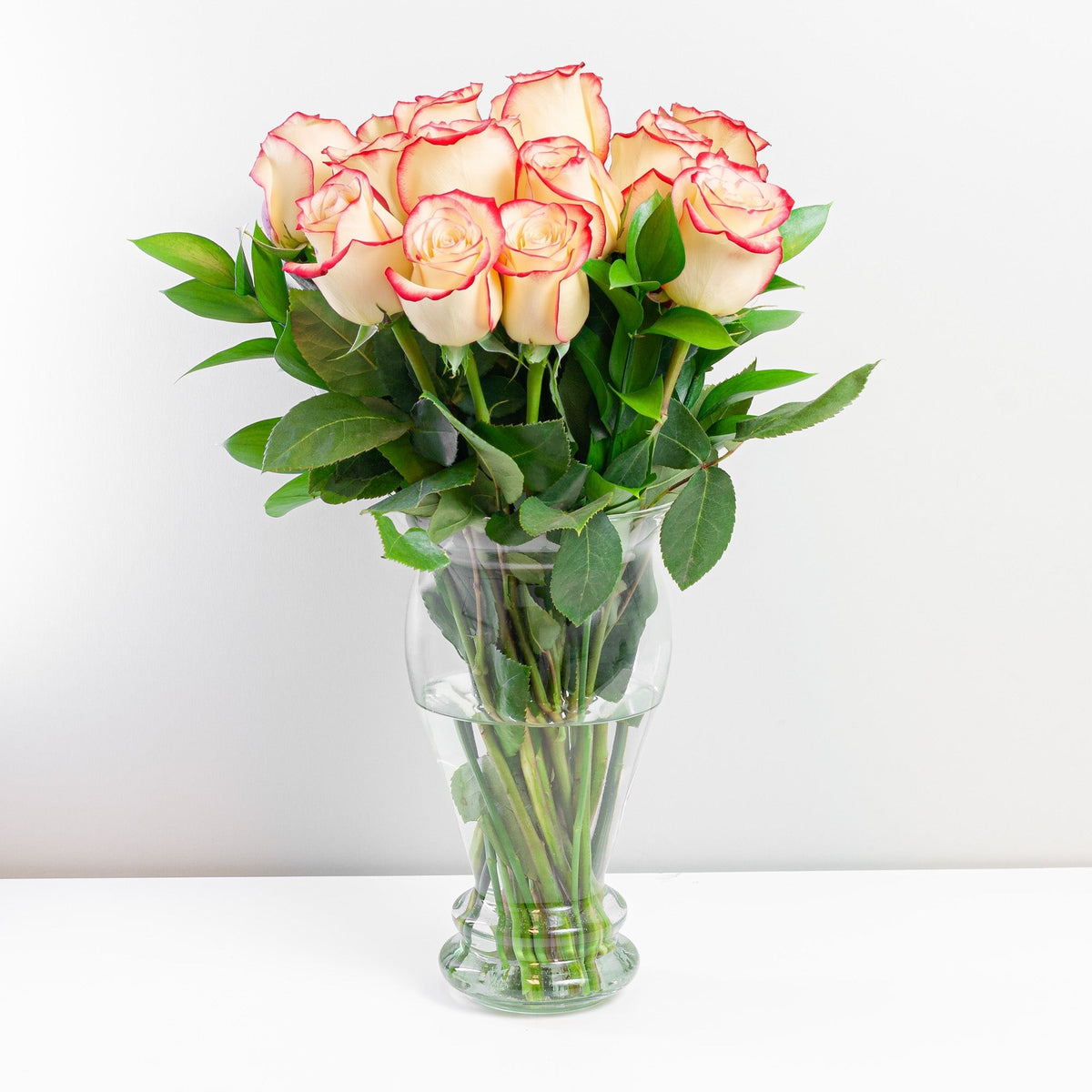 Arreglo con 15 rosas en florero modelo europeo, rosas blush (crema con borde rojo)
