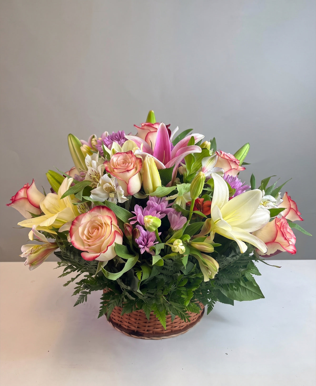 Canasta con 12 rosas, lilium y flores variadas, rosas blush (crema con borde rojo)