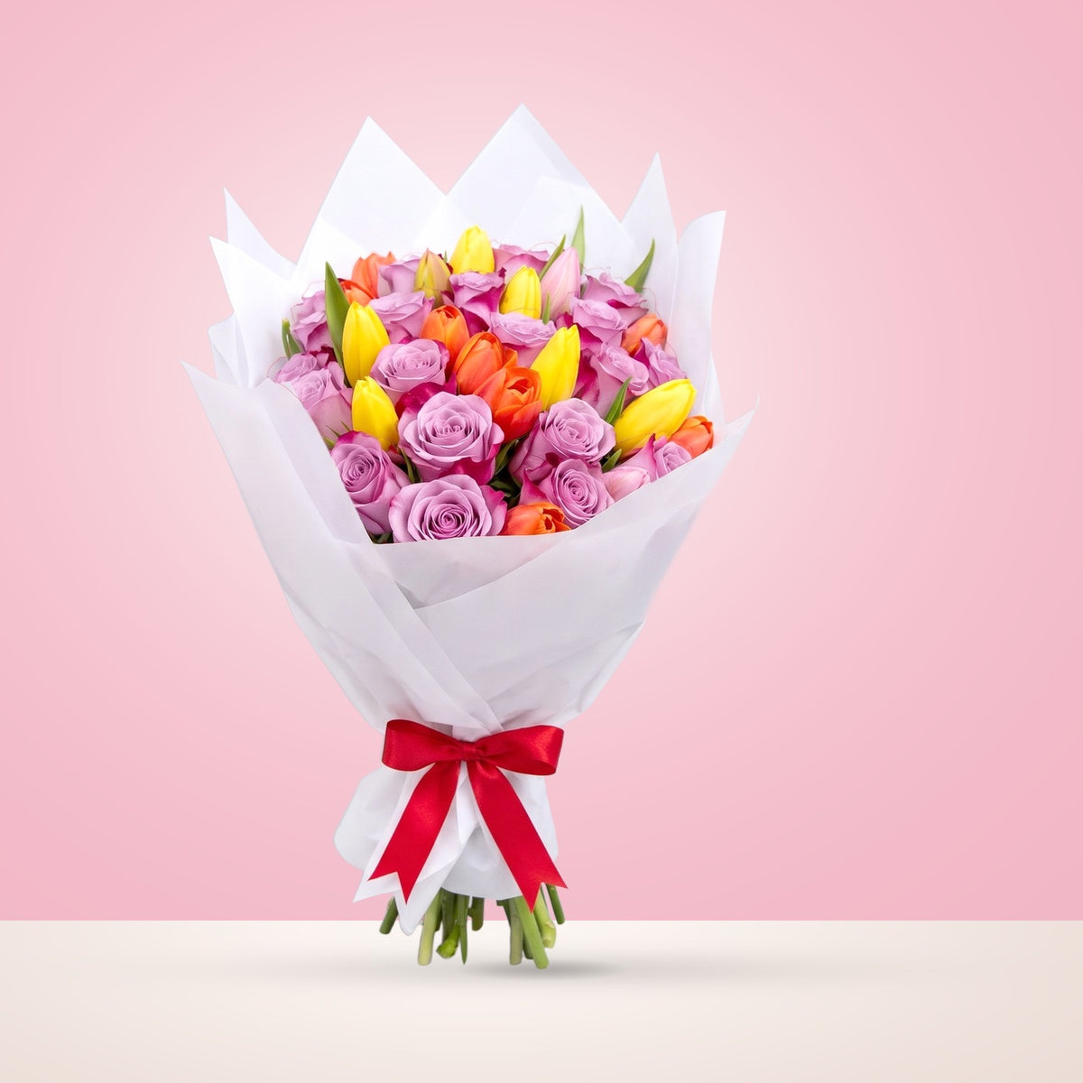 Ramo con 12 rosas lila y 10 tulipanes variados en papel blanco