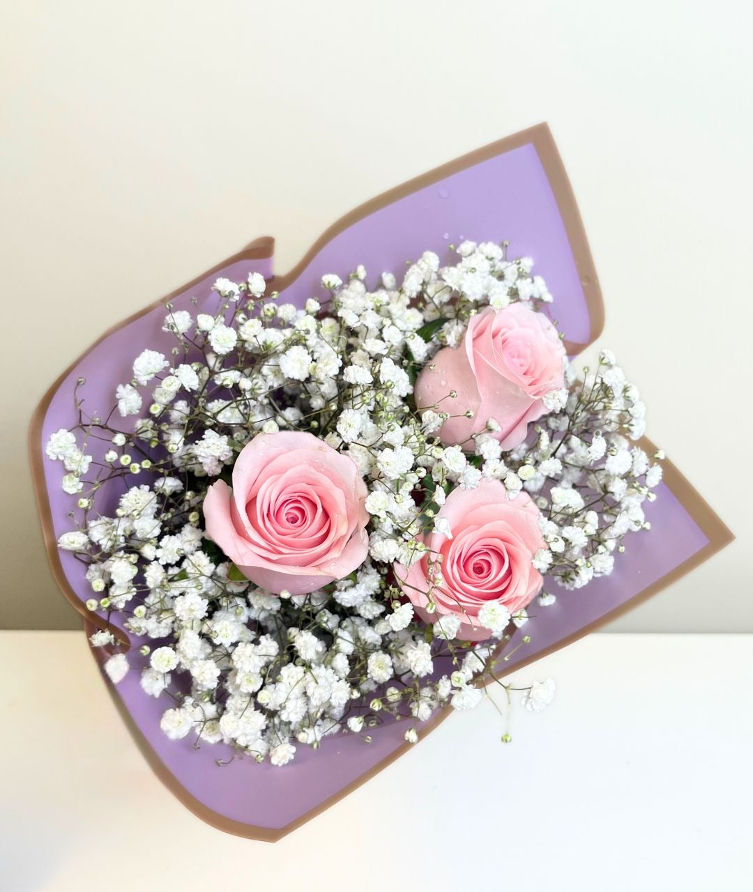 Ramo de 3 rosas con gypsophila en papel morado, rosas rosadas