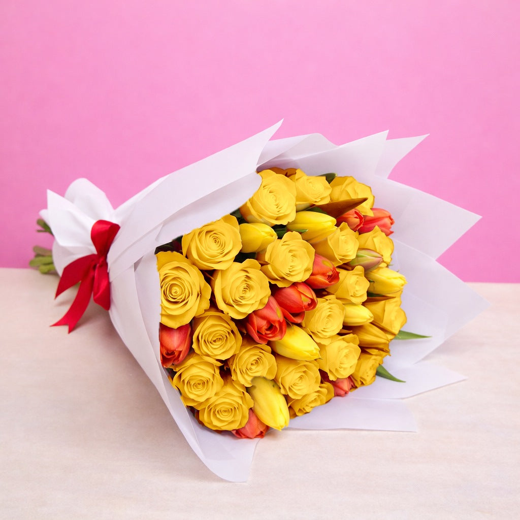 Ramo con 12 rosas amarillas y 10 tulipanes variados en papel blanco