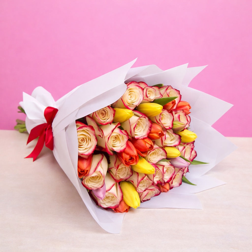 Ramo con 12 rosas blush y 10 tulipanes variados en papel blanco