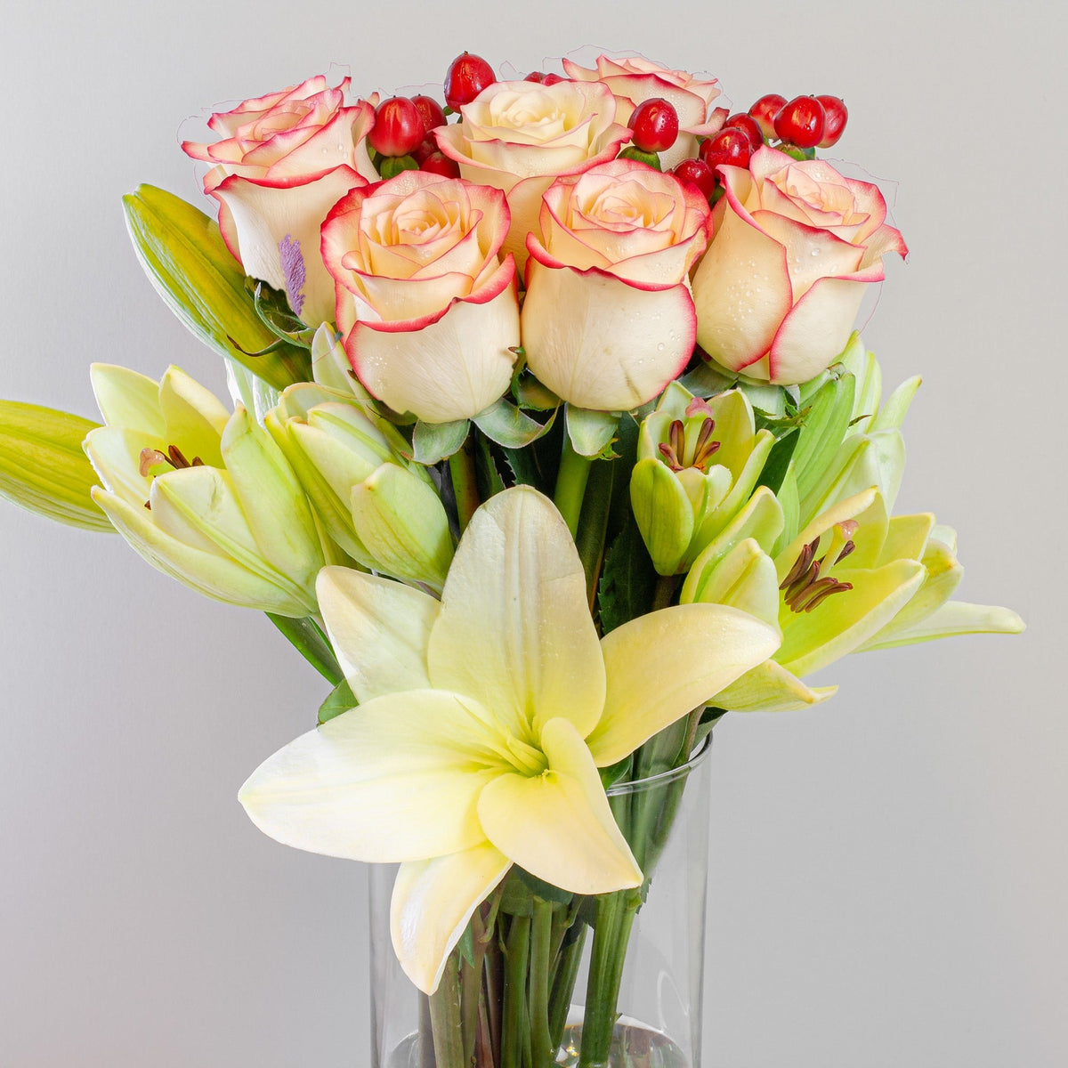 Arreglo con 10 rosas y liliums en velón, rosas blush (crema con borde rojo)