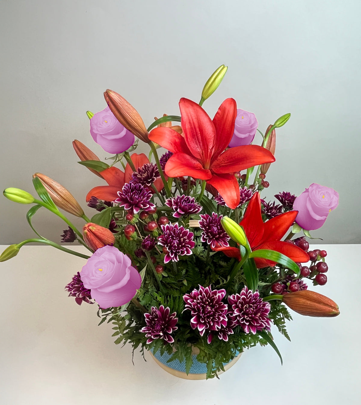 Canasta celeste con 4 rosas, liliums y maules, rosas lila