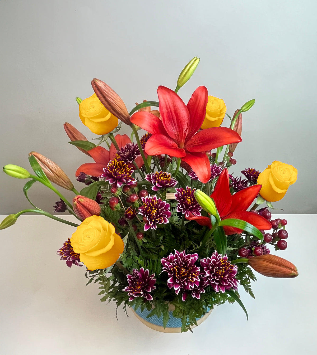 Canasta celeste con 4 rosas, liliums y maules, rosas amarillas