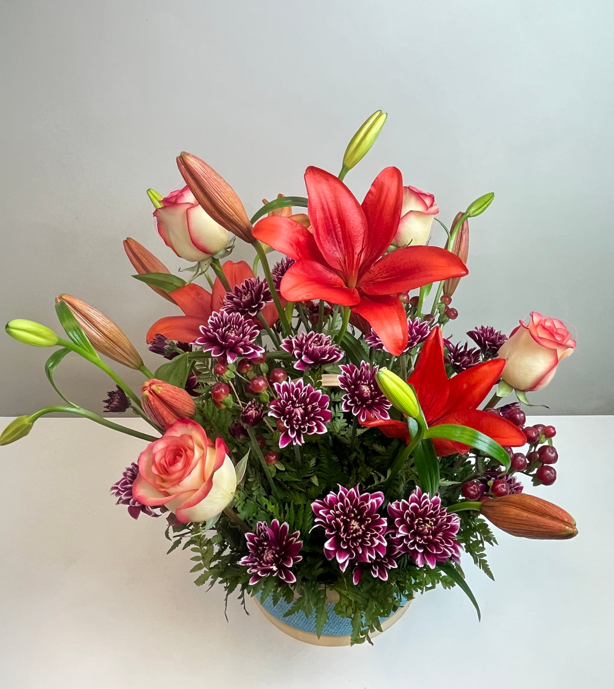 Canasta celeste con 4 rosas, liliums y maules, rosas blush (crema con borde rojo)