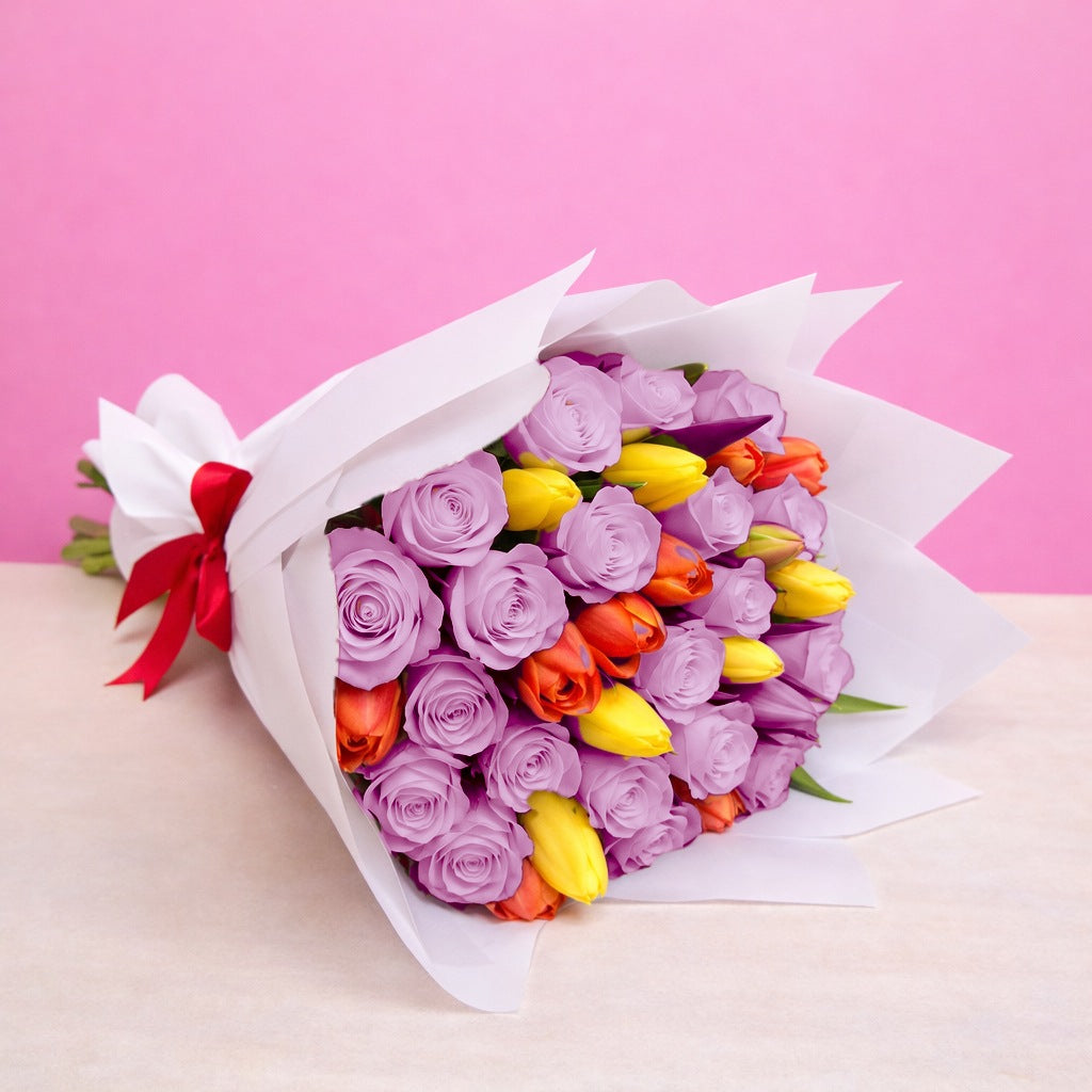 Ramo con 12 rosas lila y 10 tulipanes variados en papel blanco