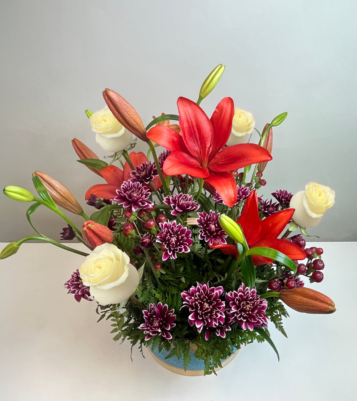 Canasta celeste con 4 rosas, liliums y maules, rosas blancas