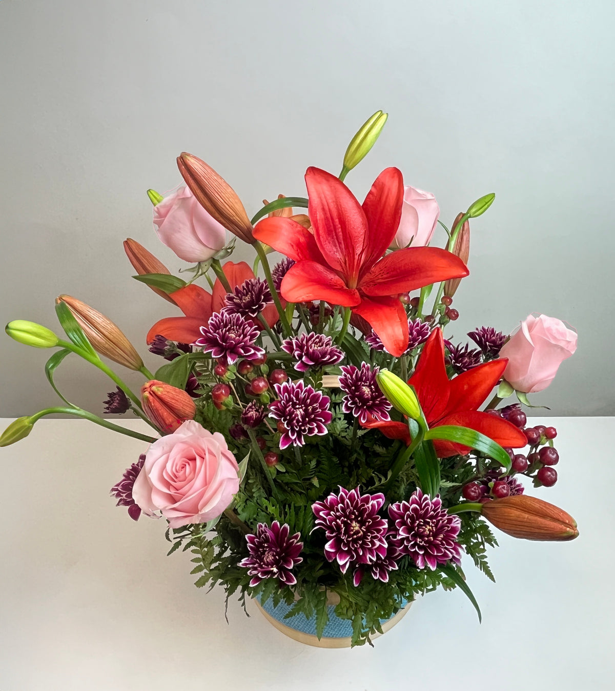 Canasta celeste con 4 rosas, liliums y maules, rosas rosadas